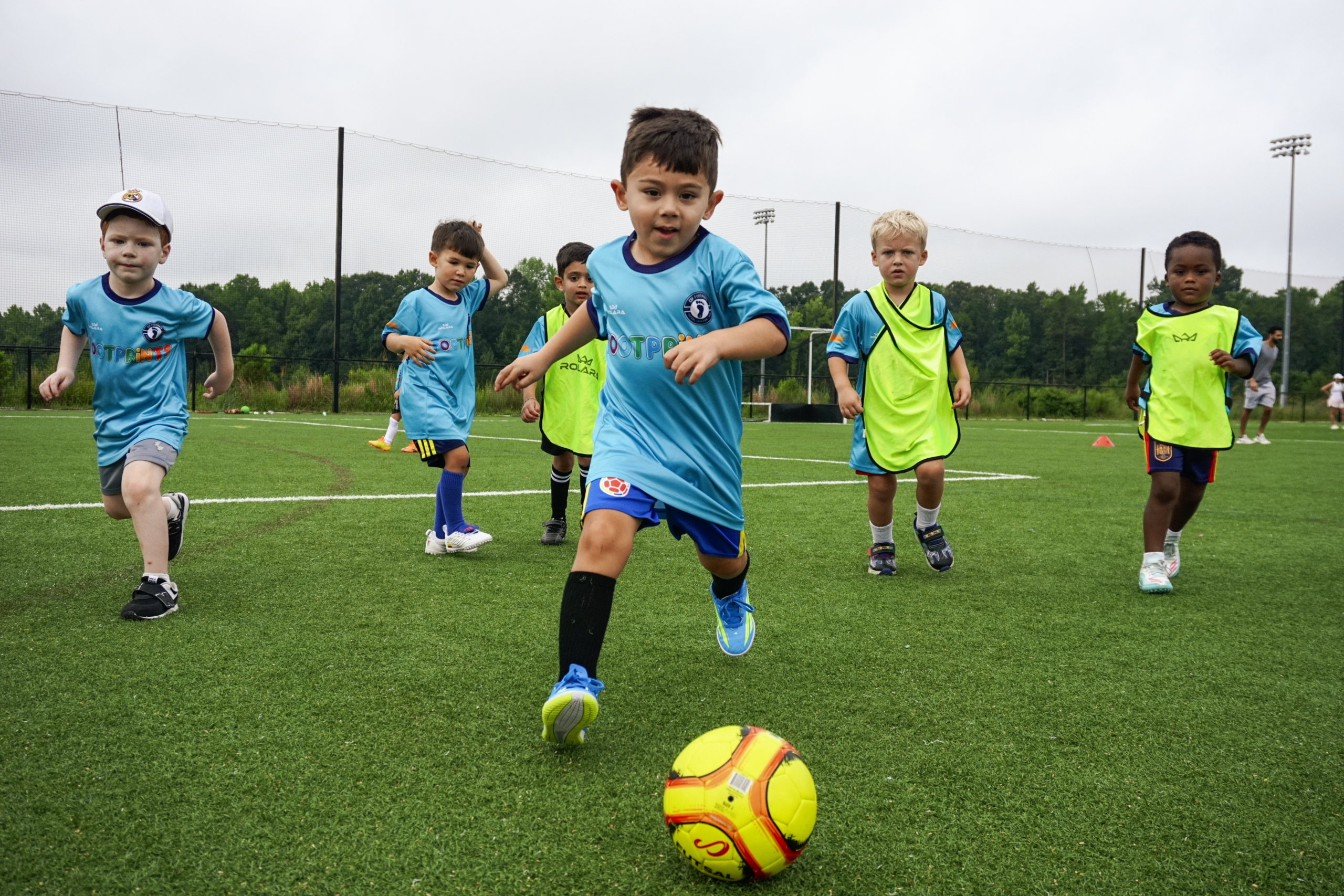 Young Footprints players running toward a soccer ball
